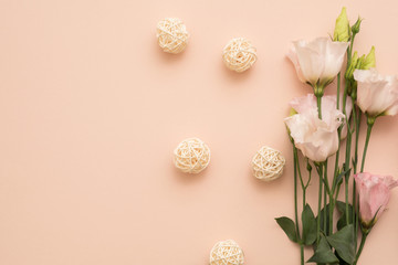 Fototapeta na wymiar Floral composition. Flat lay with delicate flowers and rattan balls arranged on peach background. Copy space.