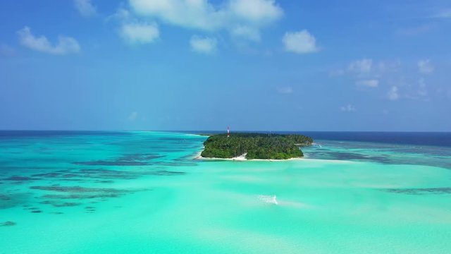 A Caribbean island, forested with palm trees.. Turquoise water in the foreground. Dolly out with with a pedetestal up, wide angle