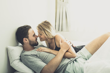 Obraz premium Loving happy couple in love smile kissing and hug each other on the bed, in big bedroom, Love story concept