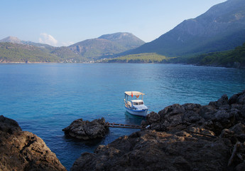The boat is anchored near the cliffs of the sea.