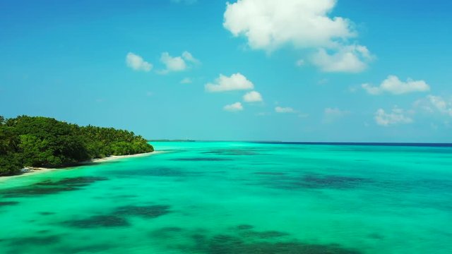 Aerial view, flying away sideways from a tropical island with palm trees on it. In the turquoise  Caribbean Sea. Truck left