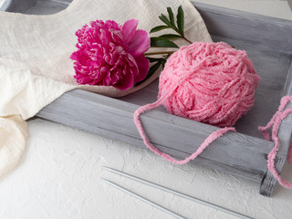Pink thread on a gray tray and a large beautiful pink peony, concept hand made, copy space.