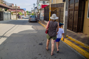 a boy walks with his mother through the narrow streets of the city on a hot sunny day