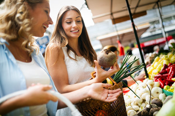 Woman buying fruits and vegetables at local food market.