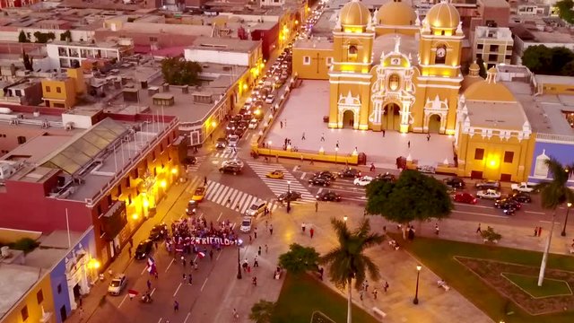a beautiful flyover of the peaceful trujillo in peru showing a riot of teachers protesting for their rights. see the magnificent cathedral and the city ilumintated at the sunset.