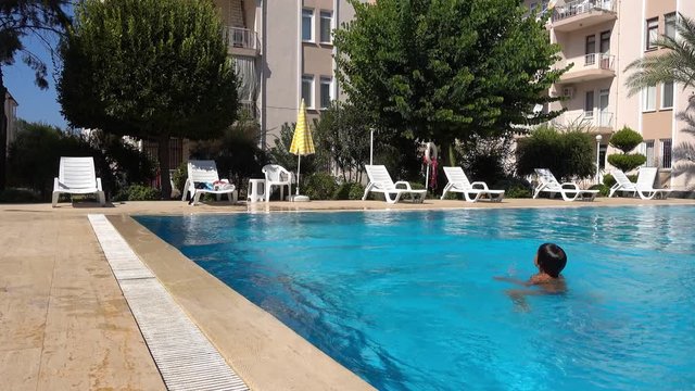 4K Kid dives head foremost in the swimming pool holding his nose