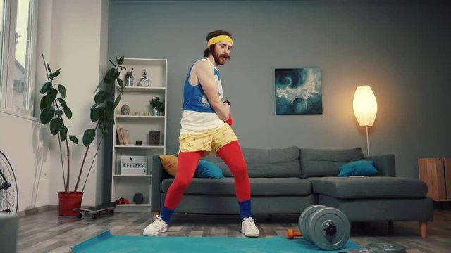 Sexy sportive young man in retro outfit enjoying music dancing and warming up preparing for intense home training.