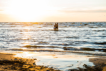 The Baltic Sea, the man and the woman I walk in bathing suits by sea at sunset