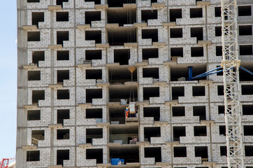 Construction site close up. On the middle floors, workers unload building materials.