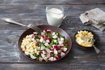 Fresh radish salad with green onions, boiled egg and sour cream on a wooden background, rustic style. Delicious homemade food	