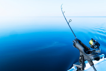 Fishing rod spinning with the line close-up. Fishing rod in rod holder in fishing boat due the fishery day. Fishing rod rings. Fishing tackle. Fishing spinning reel.