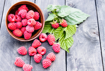 Fresh raspberry with leaves on the background of old dark boards. Selective focus.