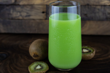 still life photo of kiwi juice, kiwi smoothie in glass on wooden background.