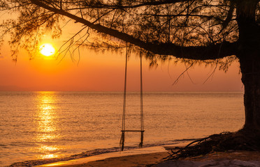 Wooden swing with beautiful sunset view on the sea beach.
