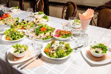 table lined with variety of dishes from which the centerpiece is dish with banquet cutting with ham and dish with several tartlets with chicken and ham