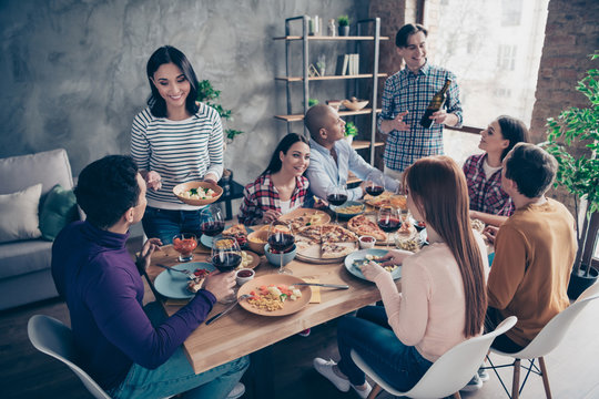 Close up photo friendly communicating festive company social crowd anniversary event treatment different race guys glasses beverage sit table shirts formal-wear sweater pullover loft room indoors