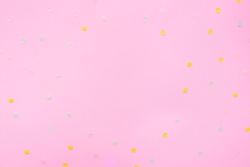 Pink pastel festive background with multicolored confetti. Copy space for your text. Flat lay style. Top view. 