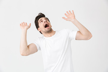 Screaming scared shocked young man posing isolated over white wall background.