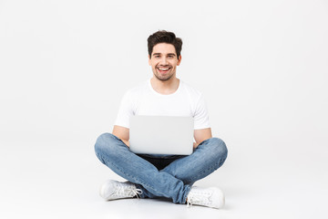 Excited young man posing isolated over white wall using laptop computer.