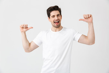 Excited young man posing isolated over white wall background pointing.