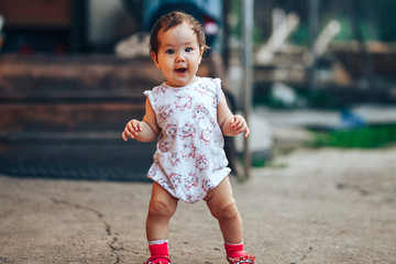 little one year old girl with dark hair play on yard at home. half-breed girl father is kazakh mother russian caucasian