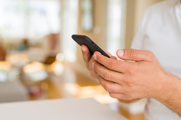 Close up of middle age man hands using smartphone at home