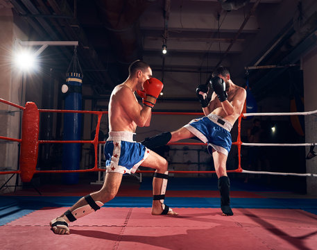 Two professional sportsmen boxers exercising kickboxing in the ring at the sport club