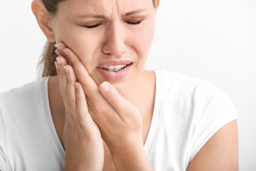 Young woman suffering from toothache on white background