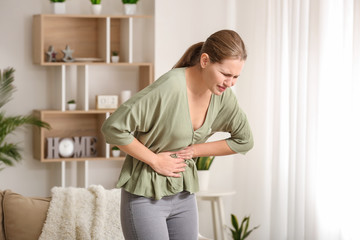 Young woman suffering from abdominal pain at home