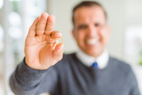 Close up of middle age man holding a engagement ring and smiling to the camera