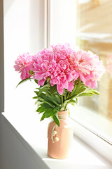 Bouquet of beautiful peony flowers on window sill