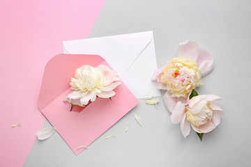 Beautiful peony flowers and envelopes on light background