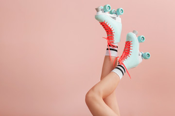 Legs of woman in vintage roller skates on color background
