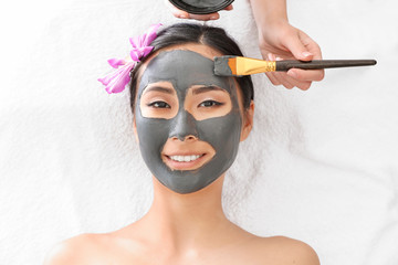 Beautiful Asian woman undergoing treatment with facial mask in beauty salon