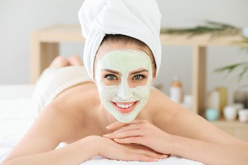 Beautiful young woman undergoing treatment with facial mask in beauty salon