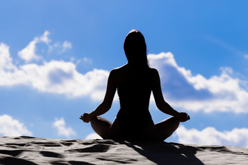 silhouette of woman meditating on sunset background