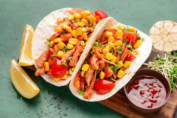 Board with tasty tacos on color background