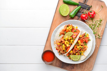 Plate with tasty tacos on white wooden background