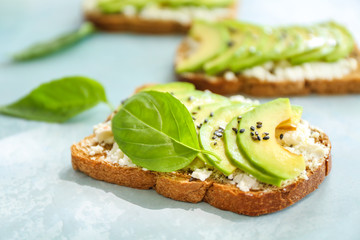 Tasty sandwiches with avocado on light color background, closeup