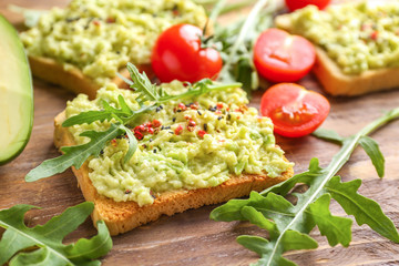 Tasty sandwich with mashed avocado on wooden background