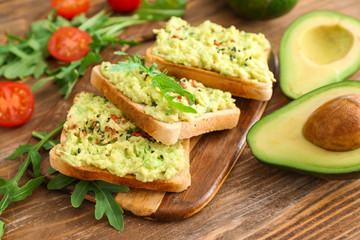 Tasty sandwiches with mashed avocado on wooden background