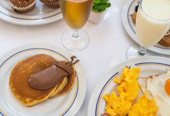 Breakfast with scrambled eggs, pancakes and juice with yogurt