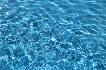 Blue and bright water surface with sun refection in swimming pool for background 