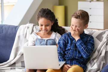 Happy adopted children with laptop watching cartoons in their new home