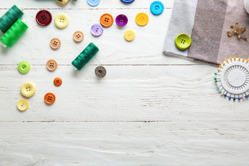 Set of sewing threads and accessories on white wooden background