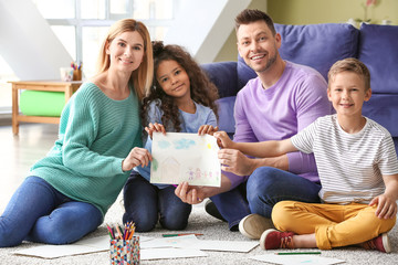 Happy couple and their little adopted children with drawing of home and family