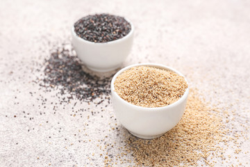 Bowls with different poppy seeds on light background