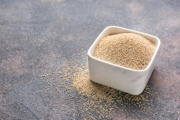 Bowl with white poppy seeds on grey background