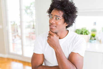 African American man wearing glasses with hand on chin thinking about question, pensive expression....