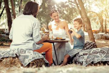 Delighted cute boy having breakfast with his parents